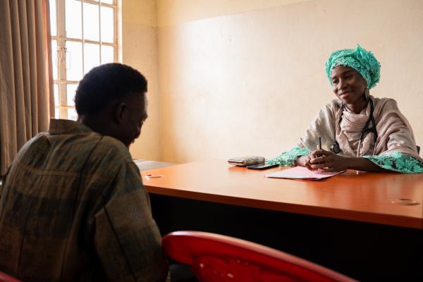 Female psychiatrist sits at table talking to a patient across from her